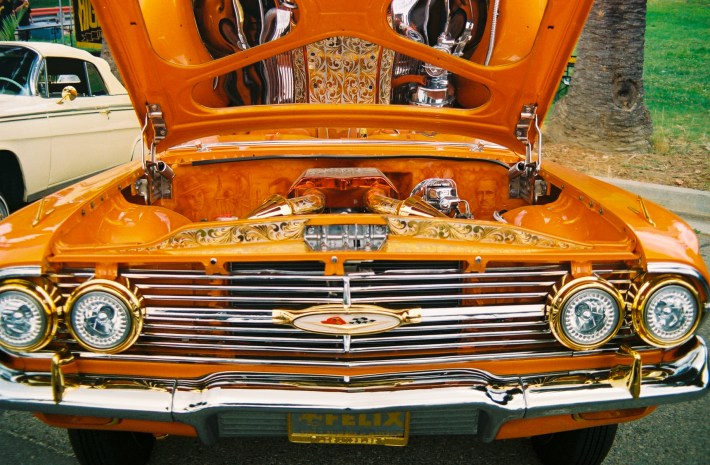 An orange lowrider with the engine hood open.