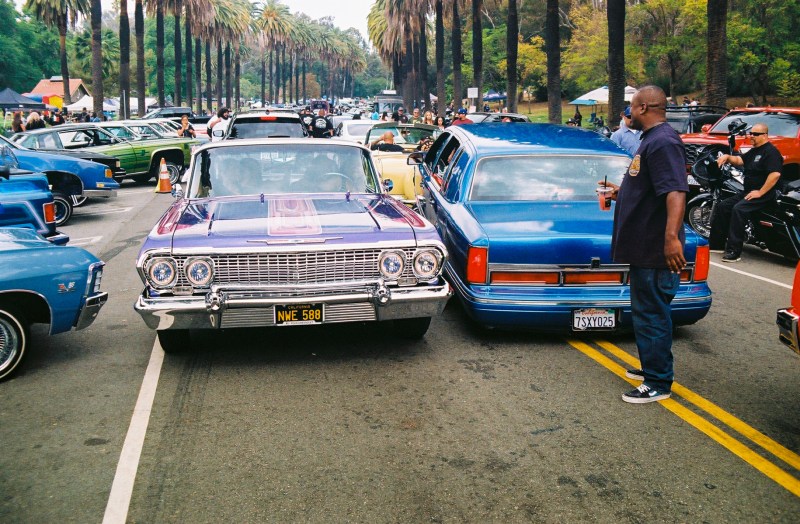 A man looks at the line of lowriders as far as the eye can see.