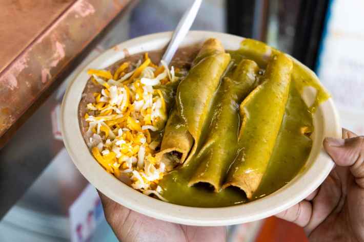 A customer holds a plate of taquitos at Cielito Lindo at Placita Olvera in Los Angeles on March 07, 2020. Photo by Brian Feinzimer for L.A. Taco