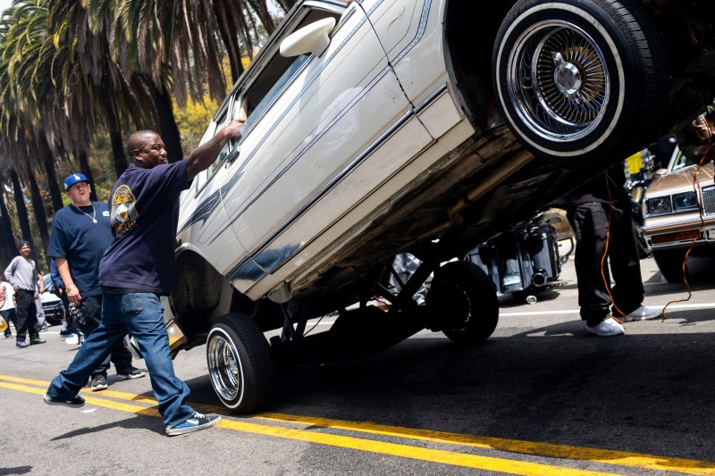 Man holds lowrider as it jumps up and down.