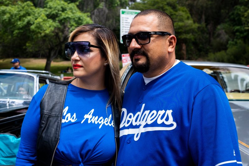 A couple wearing Dodger attire and sunglasses.