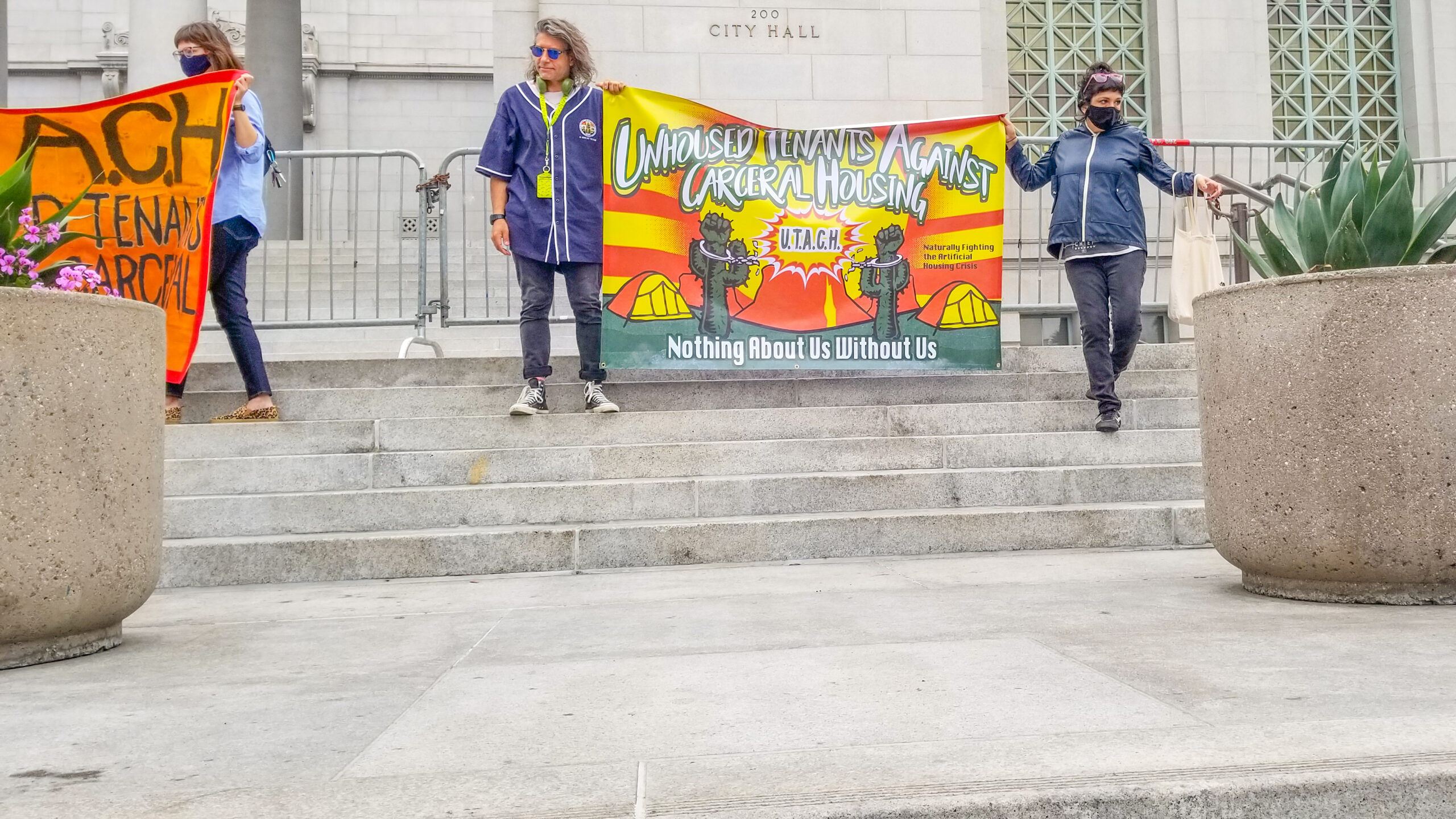 Two organizers hold up a UTACH banner in front of Los Angeles City Hall on May 19, 2021.