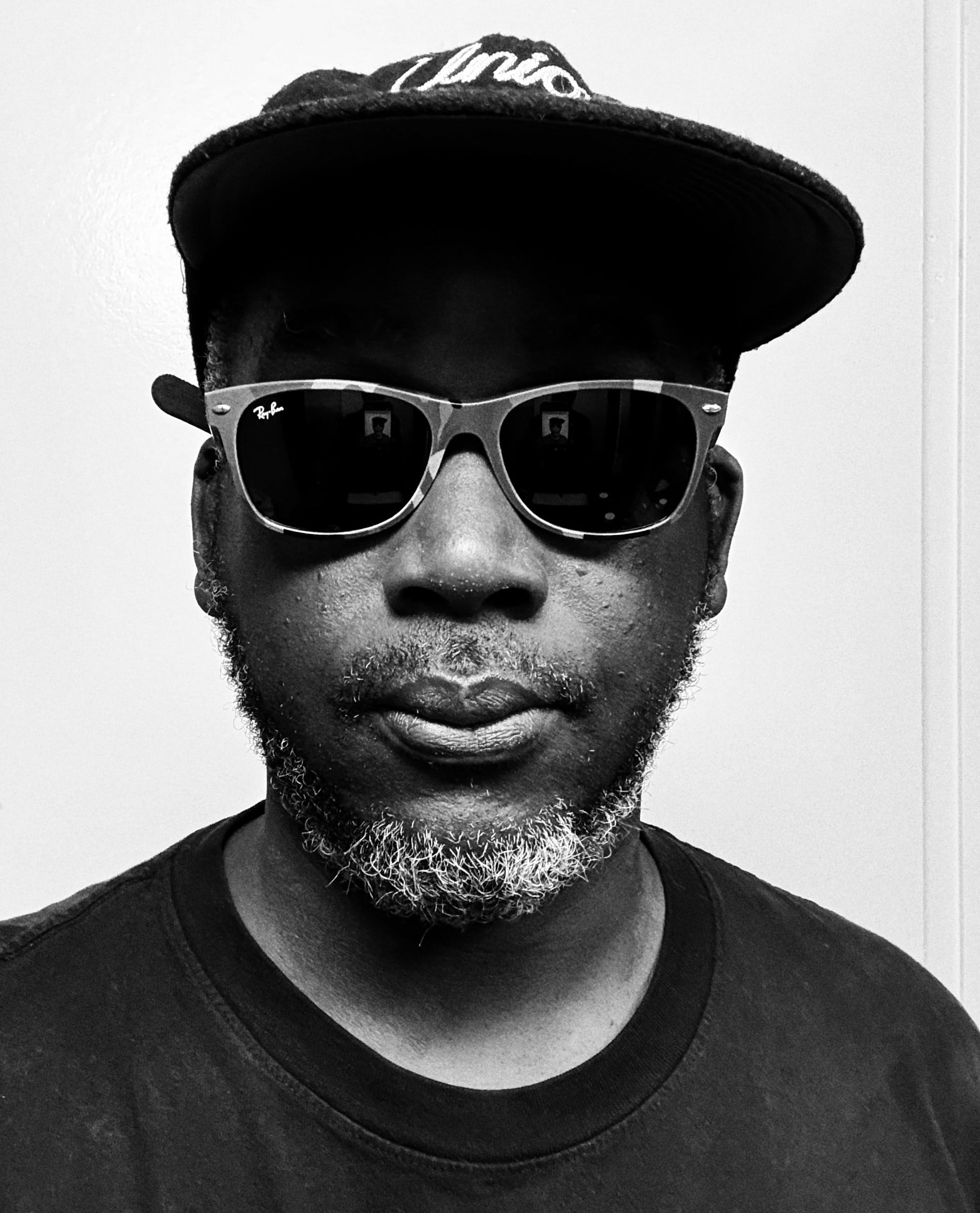 a black and white photo of a man in sunglasses and a cap