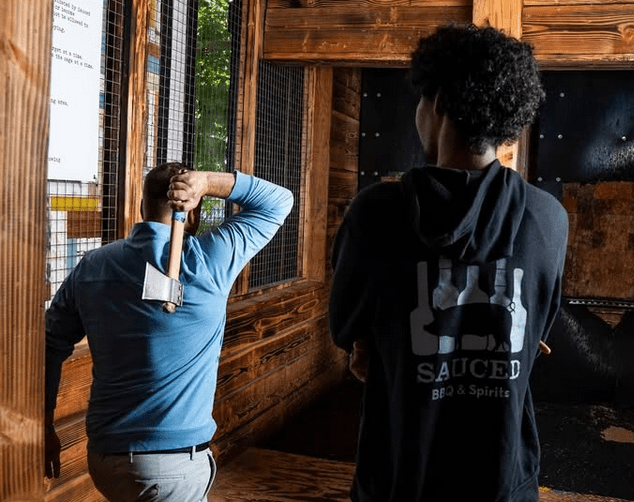 Two men throwing axes at a bar