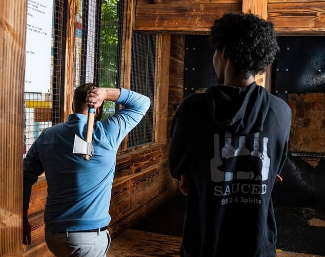 Two men throwing axes at a bar