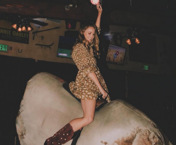 A wman riding a mechanical bull at Sadfdle Ranch