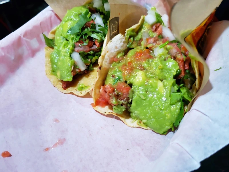 Three tacos topped with fresh, bright green guacamole. Photo from the L.A. TACO archives.