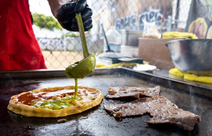 Green salsa being ladled onto a picadita de cecina that's on the griddle