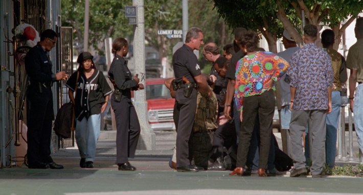 Justice observes a group of men being detained by police on 43rd Place. Screenshot via Columbia Pictures.