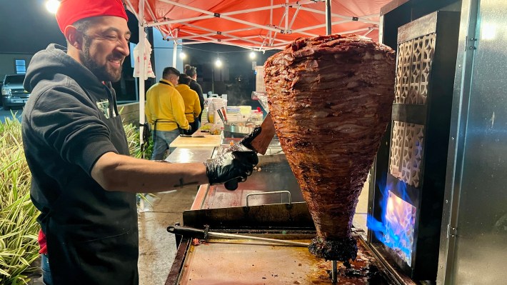 Owner Cesar "El Guapo" Perez slicing pork from a trompo at Mexitaco