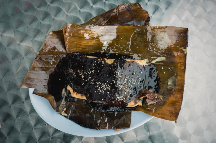 Tamal topped with a sesame seed-sprinkled mole negro, emanating the flavors and aromas of chocolate, herbs, and nuts, at Tamales Veracruz Y Mas in Los Angeles, CA