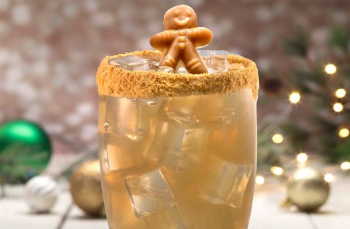 A cocktail rimmed with sugar and bearing a tiny gingerbread man