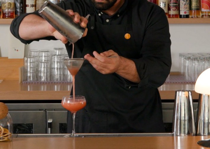 Bartender mixing a cocktail with a sieve at Asterid restaurant in Los Angeles