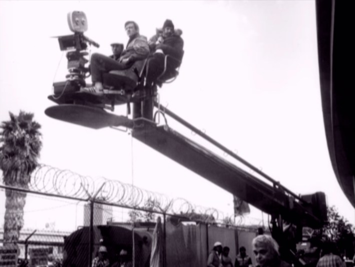 Behind the scenes photo of director Brian De Palma (right) on a camera crane shooting Scarface in DTLA.Photo via Universal Pictures