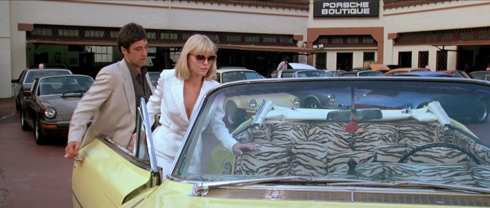 Tony (Al Pacino) escorts Elvira (Michelle Pfeiffer) to his car after looking at a new Porsche. Screenshot via Universal Pictures.