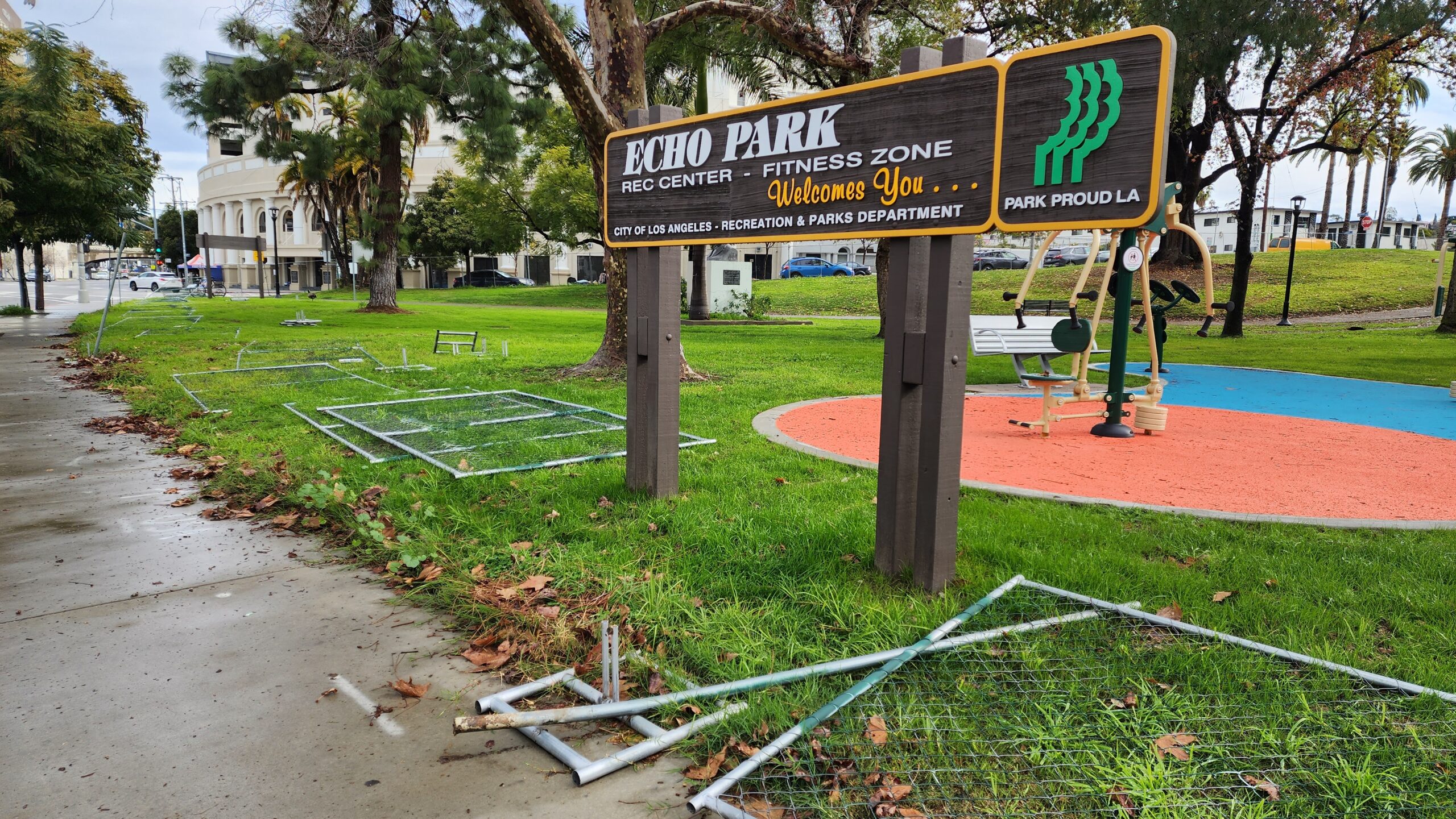 Fencing materials lay on the grass after in front of Echo Park Lake sign on the northwest side of the park.