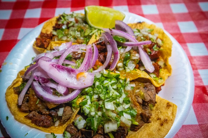 Four meaty, salsa-slathered tacos on yellow tortillas from Angel's Tijuana-Style Tacos