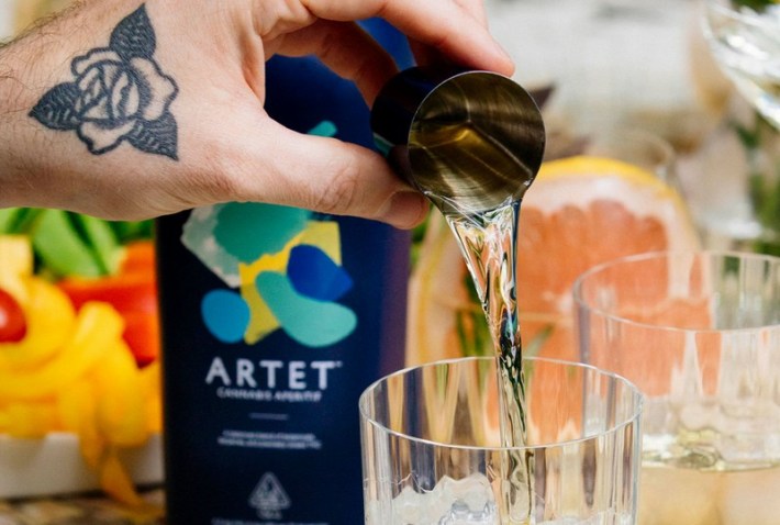 A jigger of Artet being poured into a glass beside a bottle of Artet