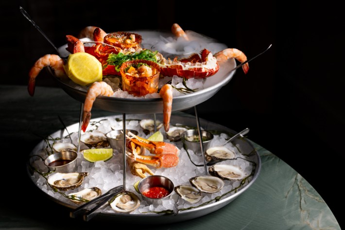 A seafgood tower with shrimp, oysters, crab claws, and agauchile shooters