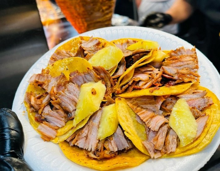 A ring of five tacos al pastor on a plate