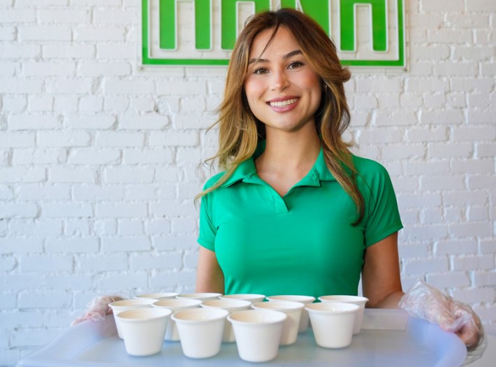 A server in a green polo shirt serves kava samples in Santa Monica