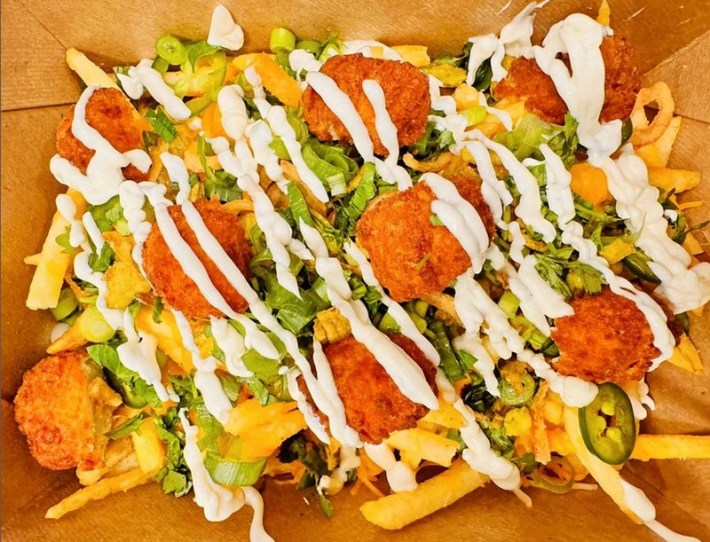 French fries covered in chicken, lettuce, jalapenos, and white sauce
