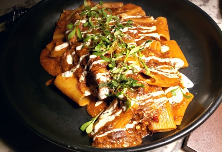 A black plate with rigatoni and al pastor-spiced short rib