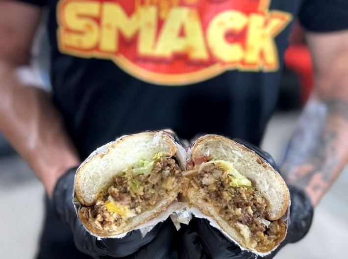 A chopped cheese sandwich being split in two by the chef of CheeseSmack