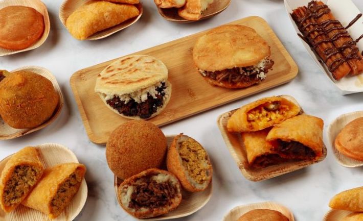 A golden spread of Venezuelan pastries and dishes, including empanadas and arepas