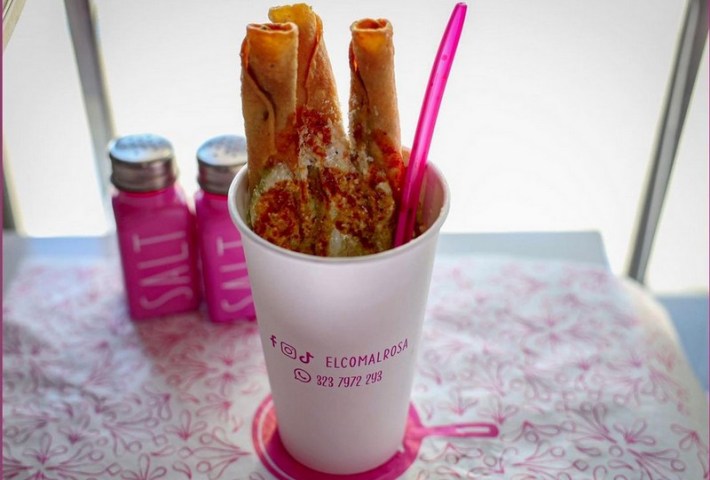 Three saucy flautas sticking upright in a paper cup