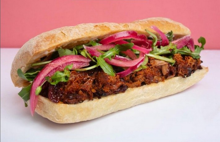 A vegan sandwich with Mexican ribs, pickled onions, arugula, mayo on ciabatta