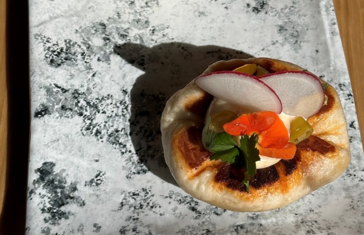 A steamed bao with chorizo and edible flowers