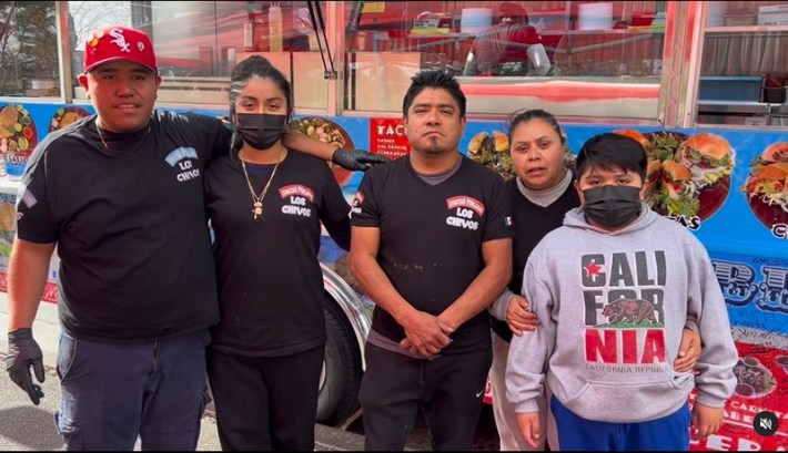 A family of five, the owners of Cemitas Poblanos Los Chivos, standing in front of their blue food truck