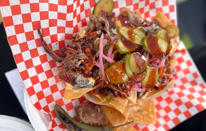Nachos covered in brisket in a basket with a red-and-white checkerboard color scheme