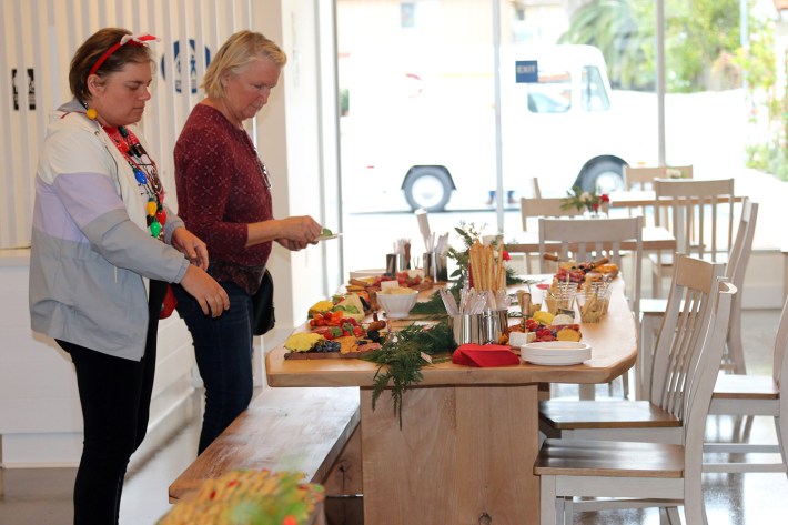 Two women stand before a set table.