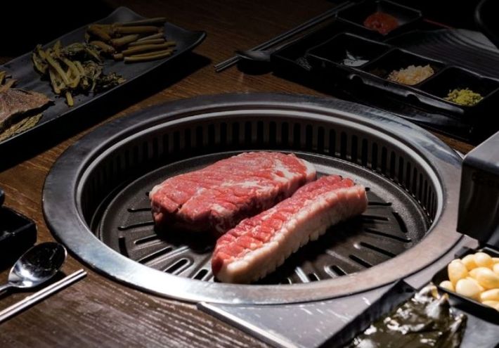 Two large pieces of pork on a grill at a Korean barbecue restaurant