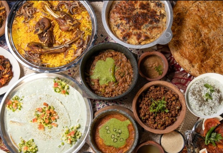 Several Yemeni dishes including lamb mandi on a yellow bed of rice