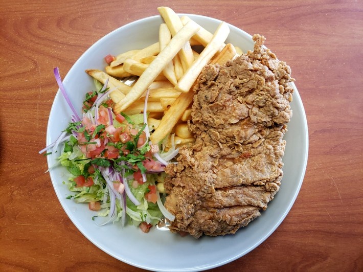 A plate of fried Peruvian chicken with French fries and salad
