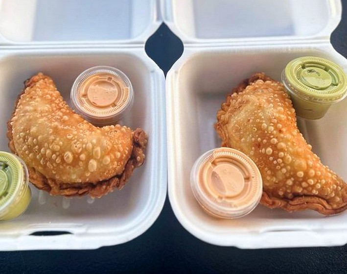 Two bubbly hot shrimp empanadas in styrophome containers