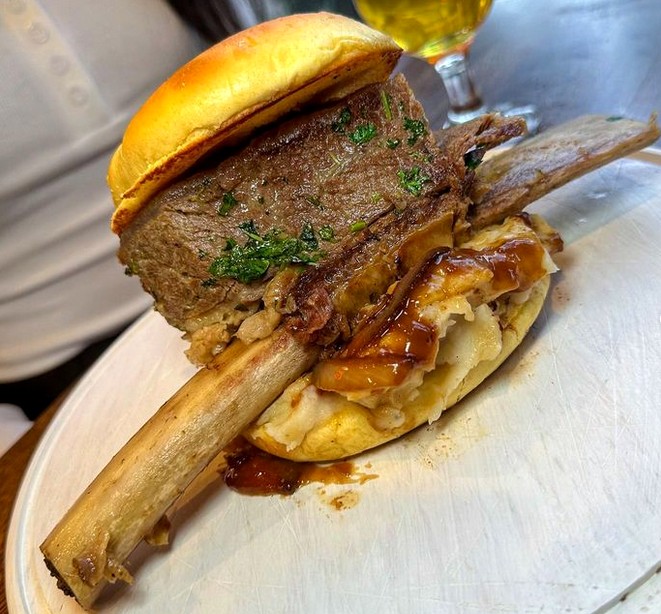 A huge burger skewered with a beef rib