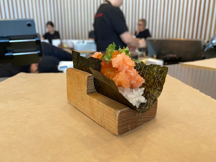 A handroll with salmon and ikura on a table