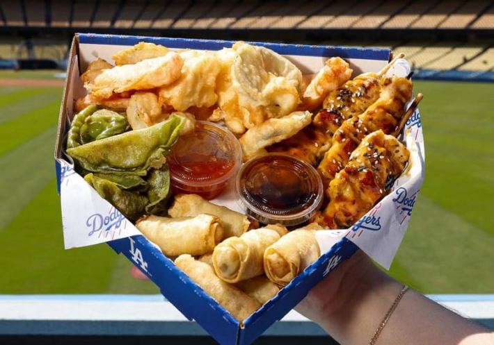 A collection of chicken skewers, Asian dumplings, and eggrolls in a home plate-shaped plate at Dodger Stadium