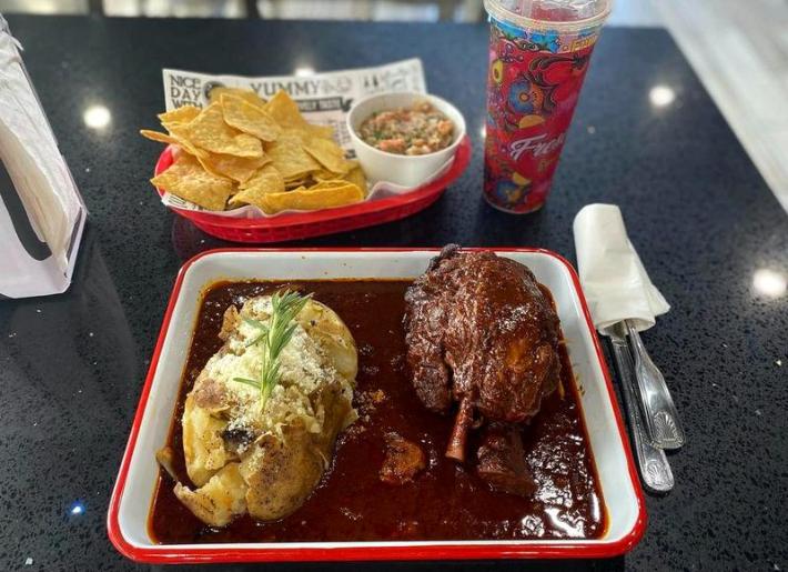 A saucy plate of chamorro with a baked potato