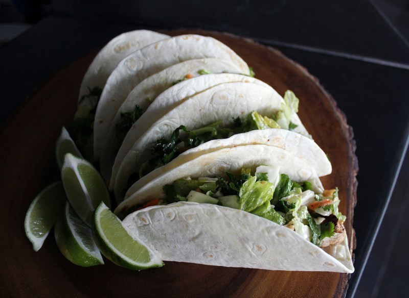 Four flour tortilla tacos with lettuce poking out of them