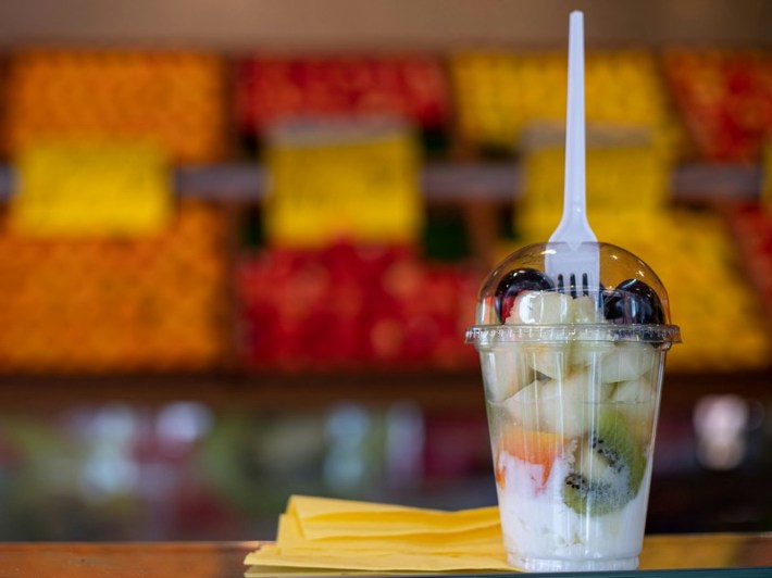 A fruit parfait with a plastic fork sticking out of it.