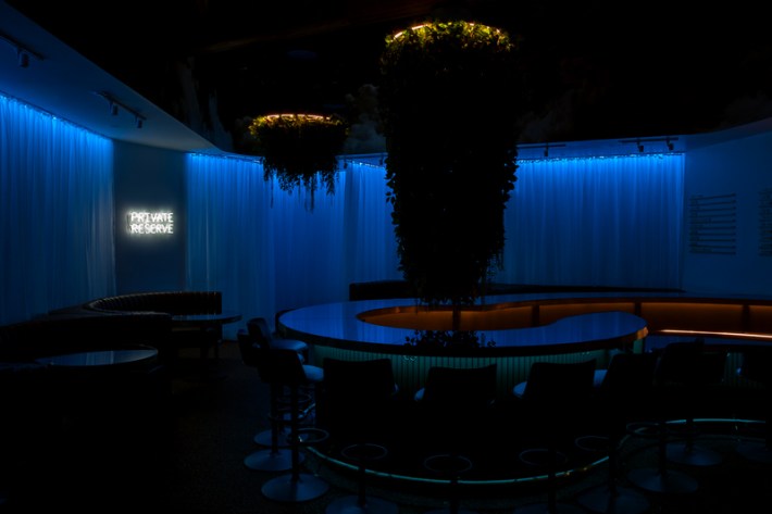 A blue-lit bar inside of a cannabis consumption lounge.