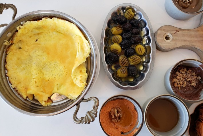 Omelet in a turneed served beside grilled olives and muhammara