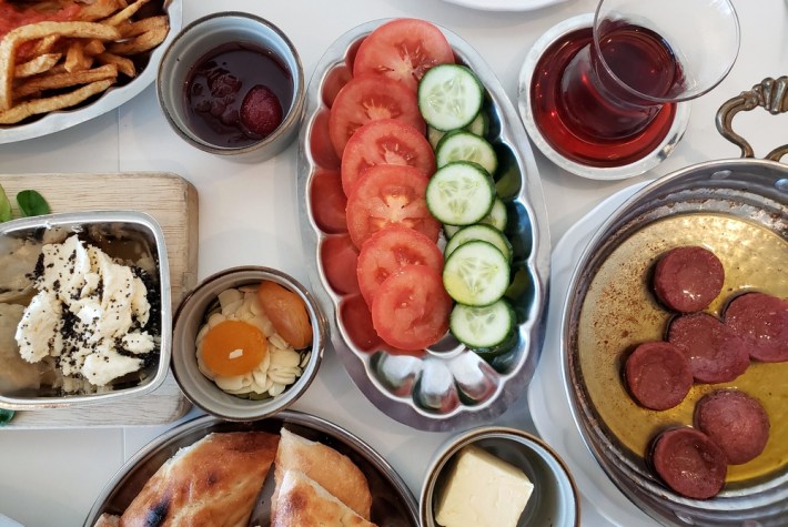 Apricots and almonds, strawberry jam, tomatoes and cucumbers, sucuk sausage, tea, bread, and butter at Alchemist Cafe & Restaurant.