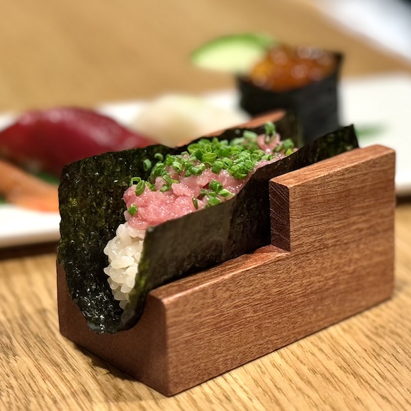 A toro handroll, with pink fish on rice inside of seaweed