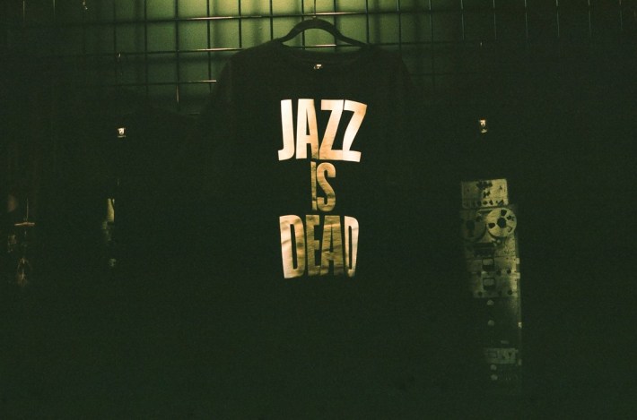 A black "Jazz Is Dead" t-shirt for sale, hanging on a wall